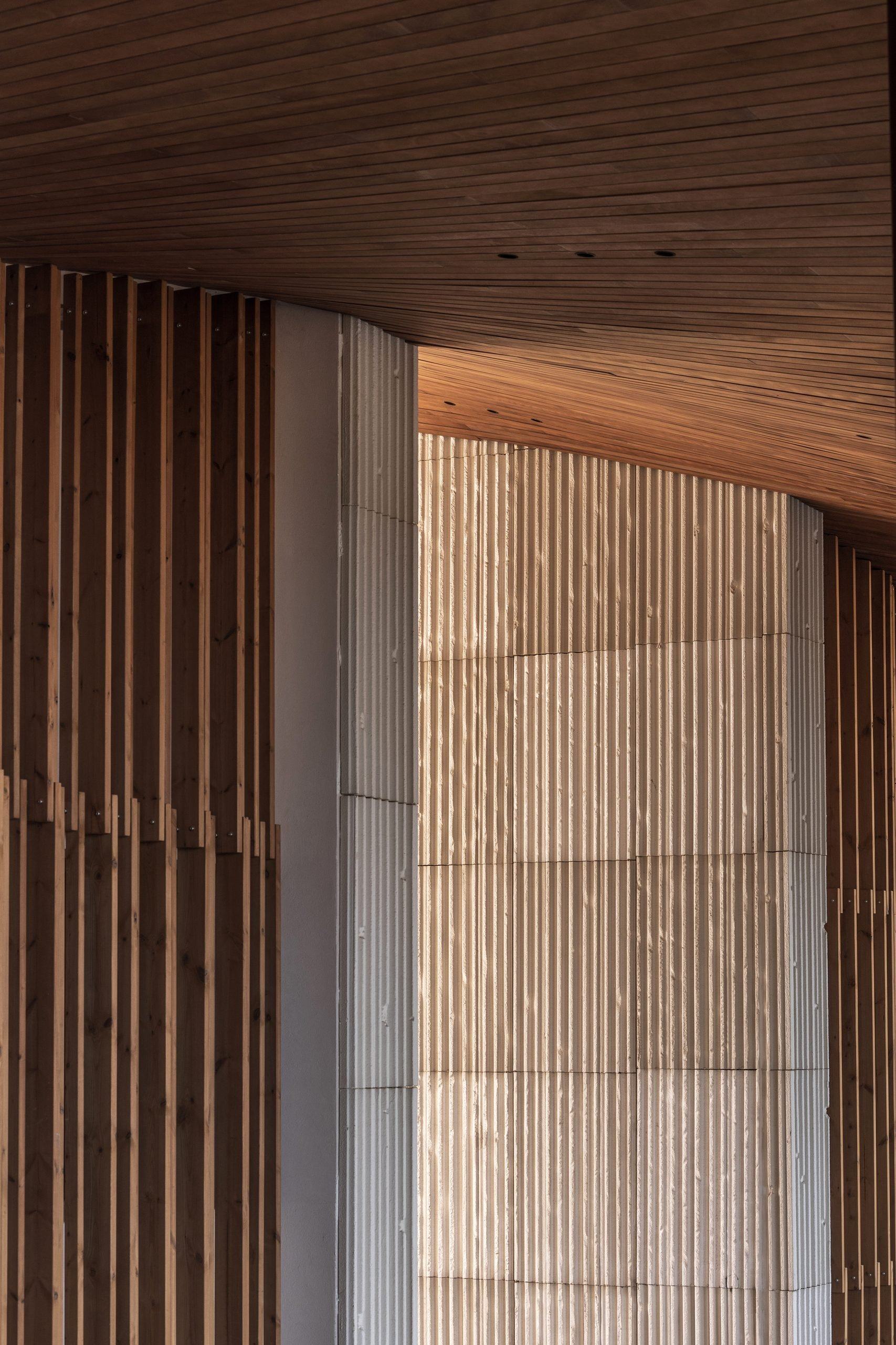 Muro curvo con listones de madera y piedra — Archidom Laguna, Costa del Sol. Fotografía de Pedro Jaén