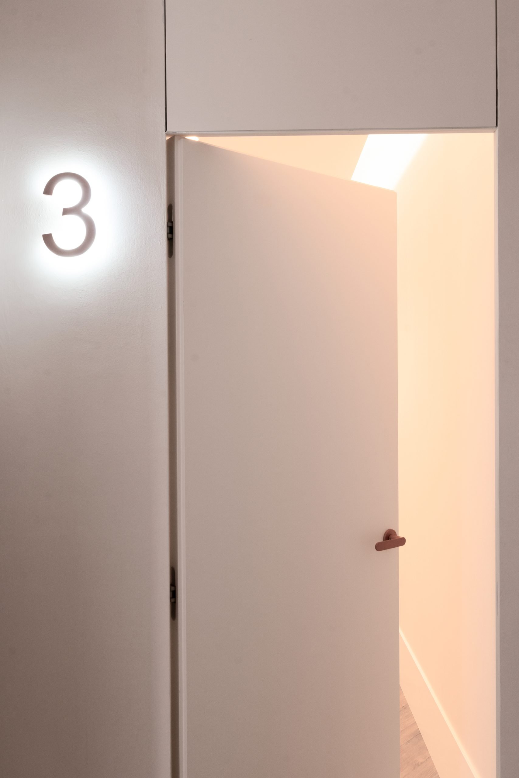 Puerta blanca con número iluminado — Atempora, Costa del Sol. Fotografía de Pedro Jaén