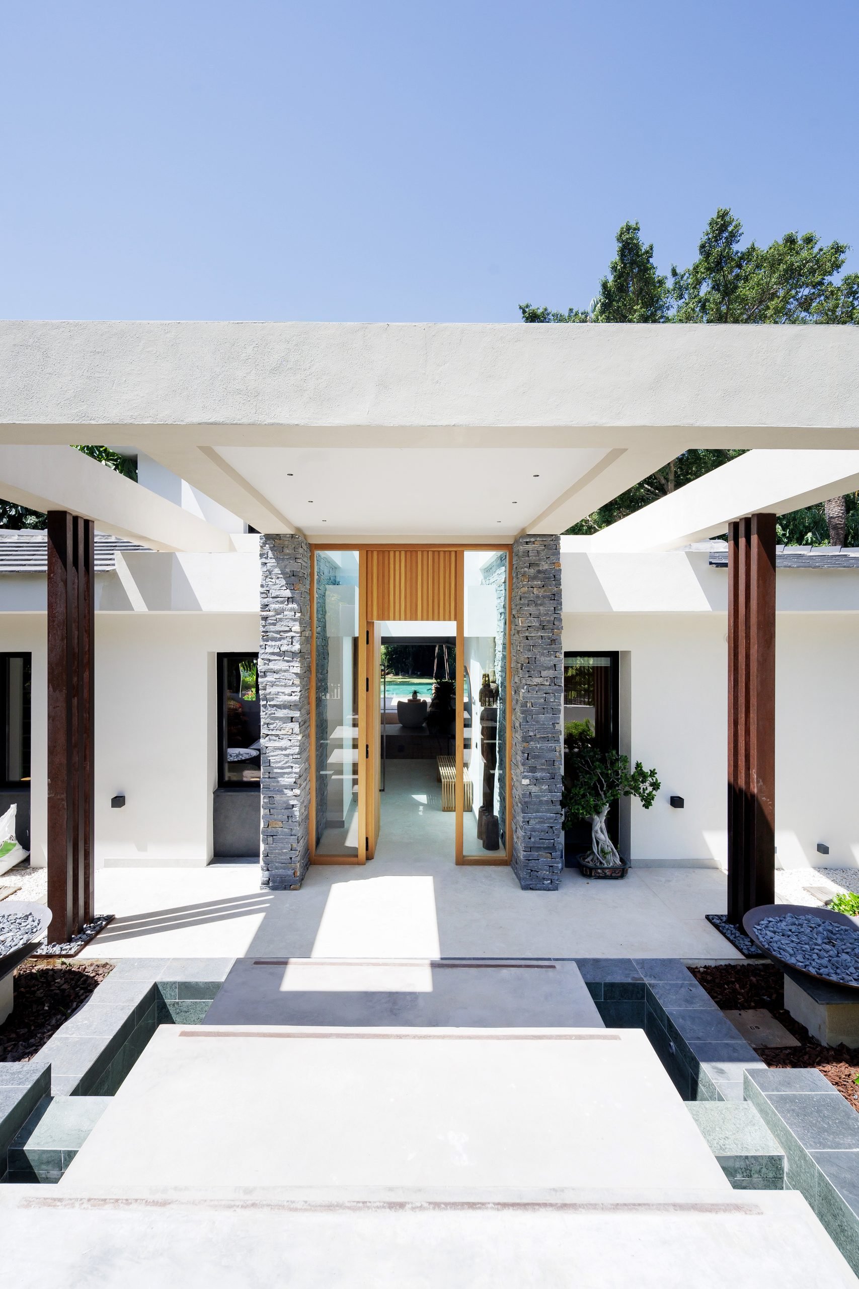 Porche de hormigón blanco con pilares de piedra y madera — Eacis Villa Lovina, Costa del Sol. Fotografía de Pedro Jaén