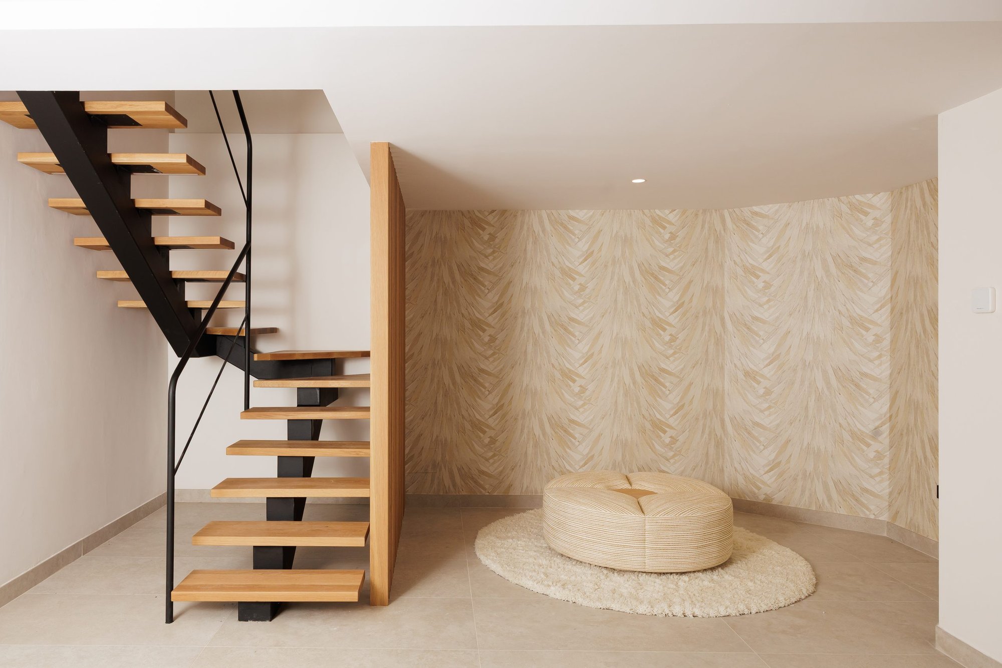Escalera de madera y puf sobre alfombra redonda — Eacis Villa Lovina, Costa del Sol. Fotografía de Pedro Jaén