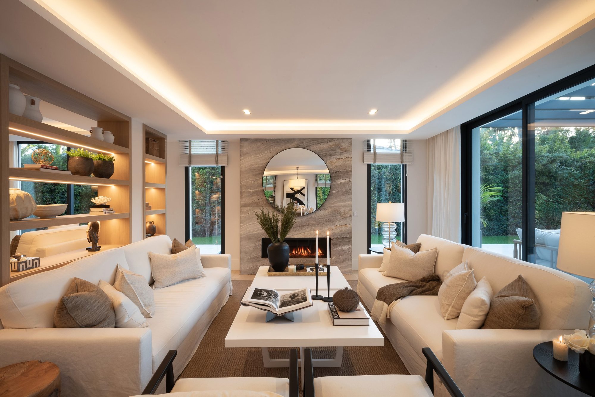 Salón con sofás claros y estantería iluminada — Grace Deco Nueva Andalucía, Nueva Andalucía, Marbella. Fotografía de Pedro Jaén
