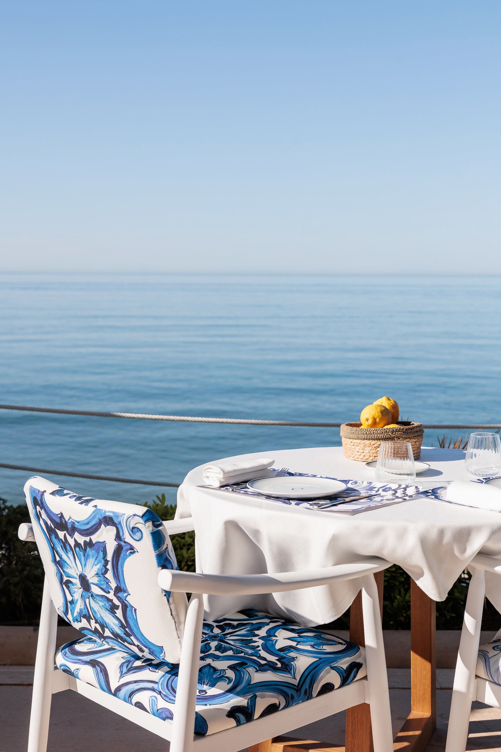 Mesa puesta frente al mar con sillas majólica — La Cabane · Marbella. Fotografía de Pedro Jaén