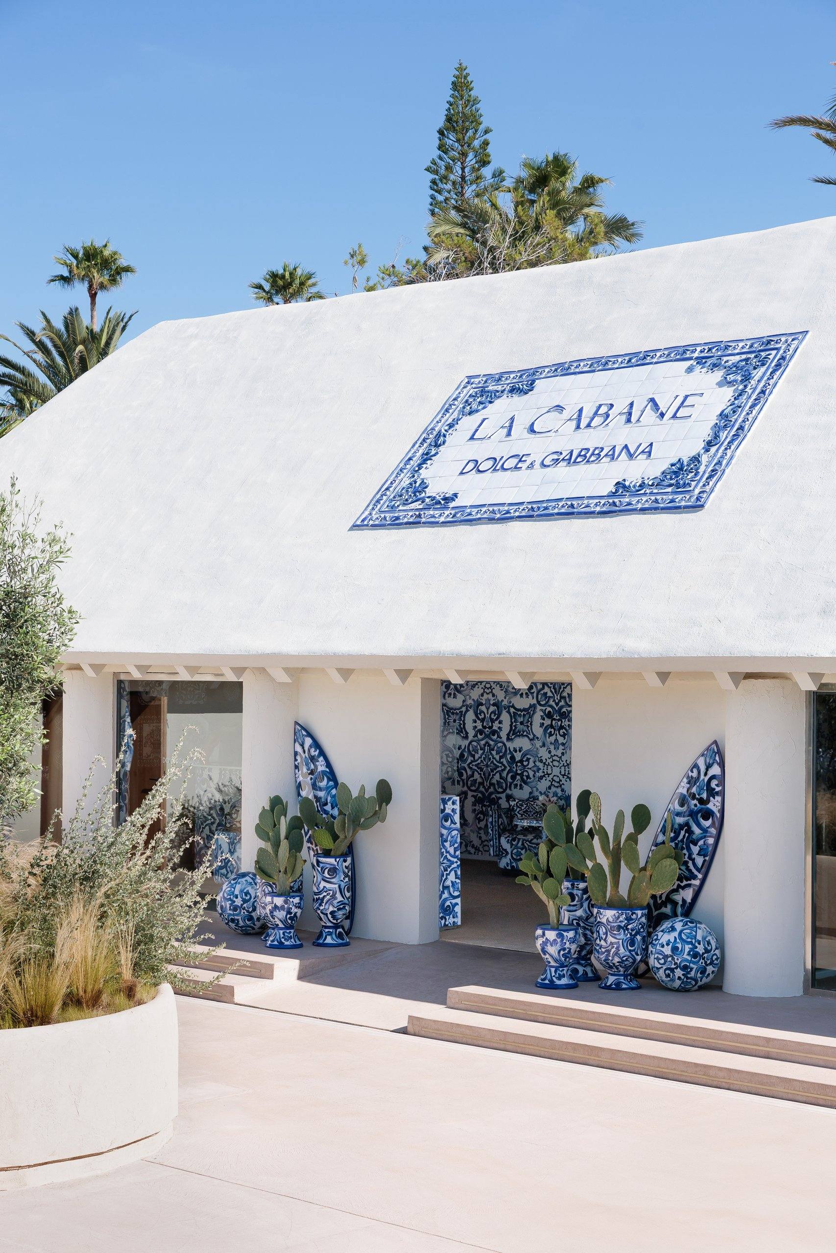 Edificio con rótulo La Cabane Dolce & Gabbana, cactus y tablas — La Cabane · Marbella. Fotografía de Pedro Jaén
