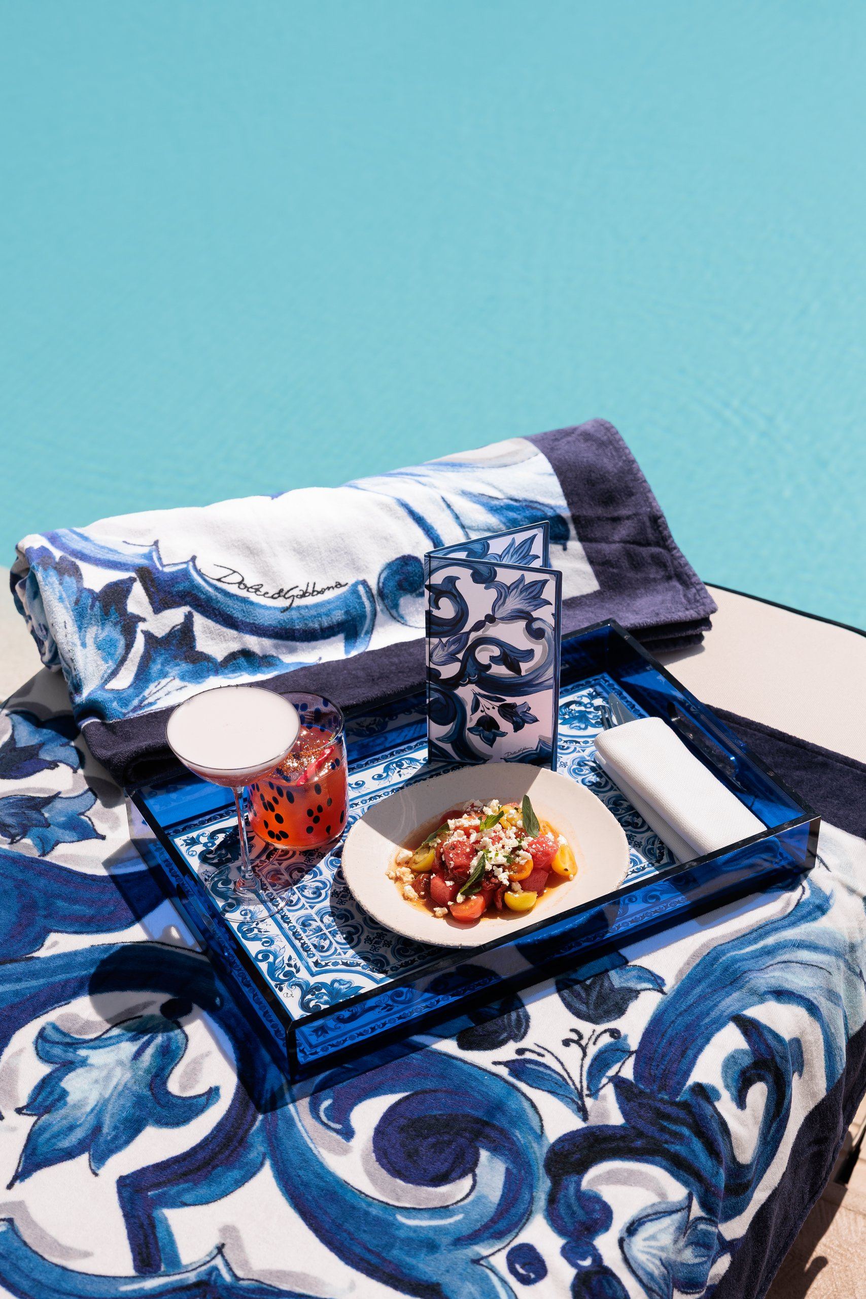 Bandeja con comida y cócteles sobre toalla Dolce & Gabbana — La Cabane · Marbella. Fotografía de Pedro Jaén