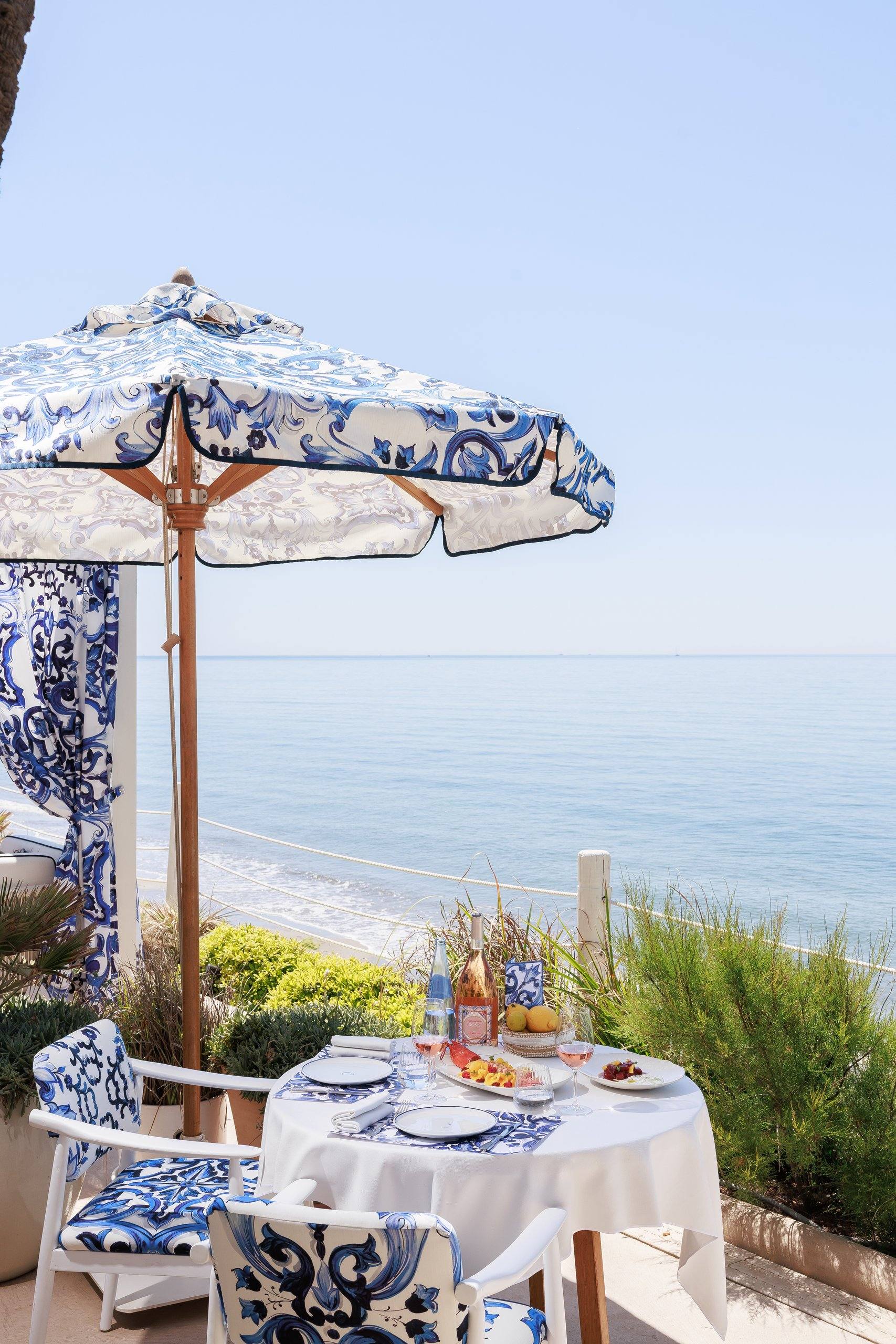 Mesa bajo sombrilla majólica frente al mar — La Cabane · Marbella. Fotografía de Pedro Jaén