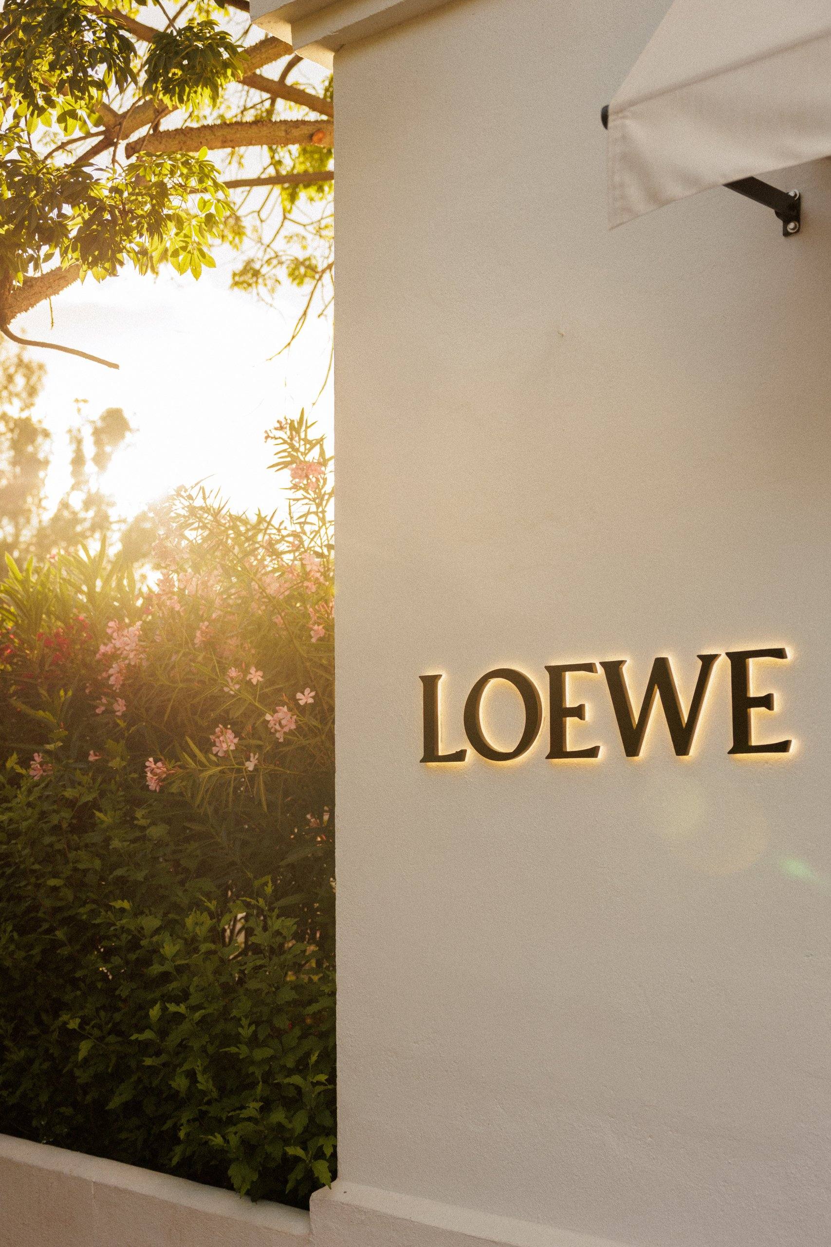 Rótulo LOEWE sobre muro blanco a contraluz — Loewe · Marbella Club, Marbella Club Hotel, Marbella. Fotografía de Pedro Jaén