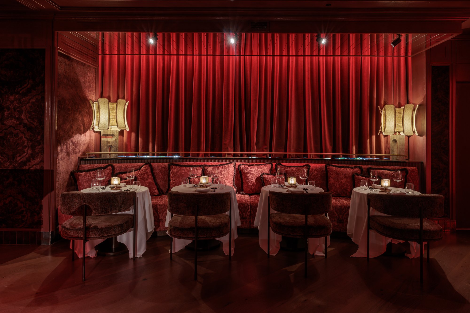 Banquetas con cojines bajo la cortina roja y lámparas de fibra — Motel · Nuevo, Marbella. Fotografía de Pedro Jaén