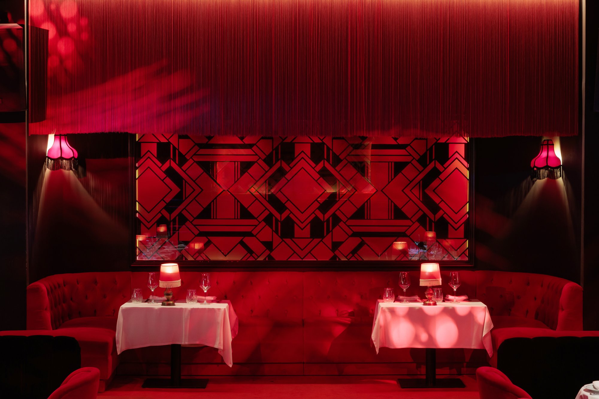 Banquetas rojas ante el panel geométrico art déco — Motel, Marbella. Fotografía de Pedro Jaén