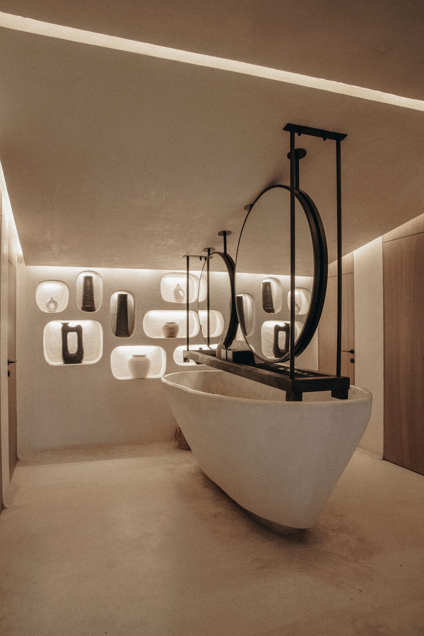 Baño con lavabo de piedra, espejos redondos y hornacinas iluminadas — Nido, Marbella. Fotografía de Pedro Jaén