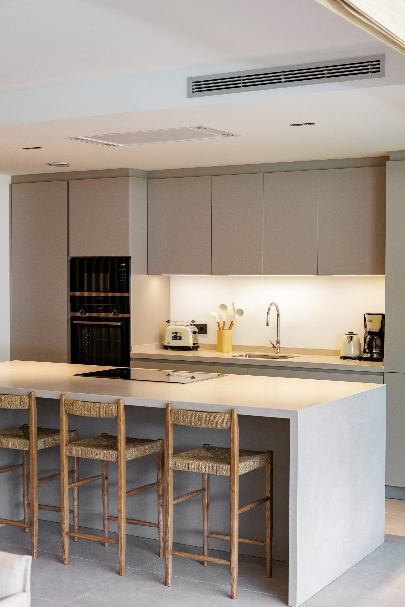 Cocina con isla blanca y taburetes de madera — Sotogrande Village Verde, Sotogrande, Cádiz. Fotografía de Pedro Jaén