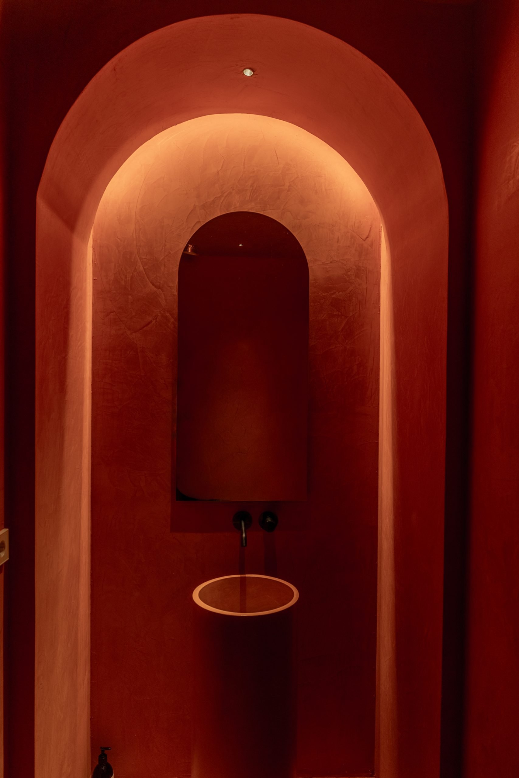 Aseo en arco con microcemento rojo e iluminación indirecta — Villa Copal, Cabopino, Marbella. Fotografía de Pedro Jaén