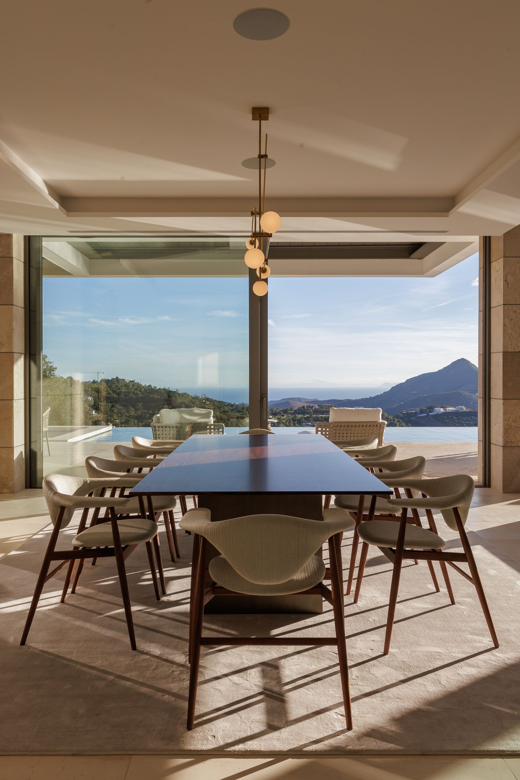 Comedor largo frente a ventanales y terraza — Villa Kaizen · La Zagaleta. Fotografía de Pedro Jaén