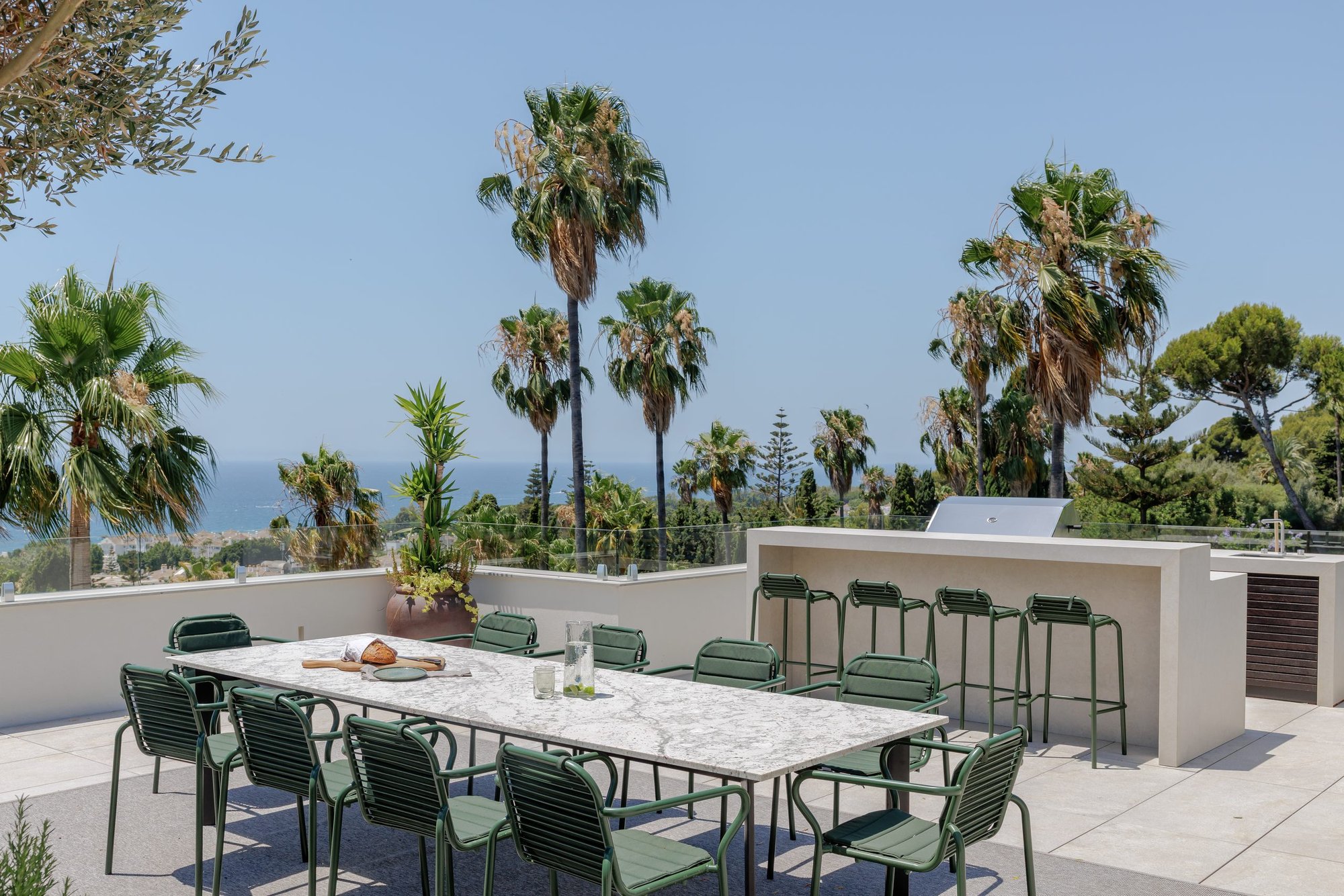 Comedor exterior con barra y barbacoa entre palmeras — Villa Kronenburg, Nagüeles, Marbella. Fotografía de Pedro Jaén