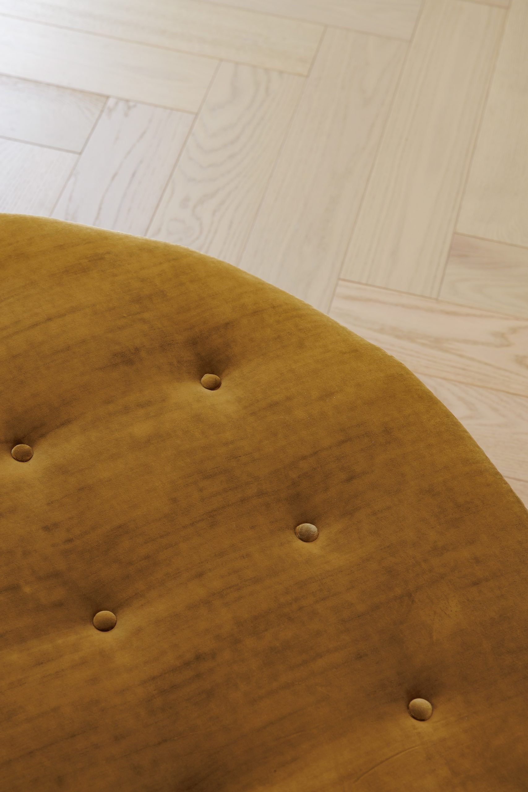 Detalle de puf capitoné mostaza sobre suelo de madera — Villa Rina 5, Costa del Sol. Fotografía de Pedro Jaén