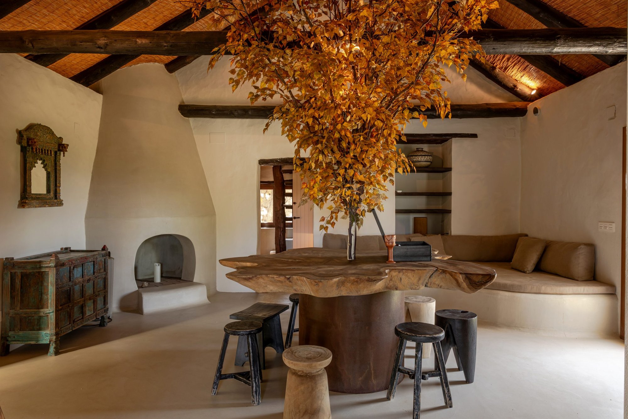 Salón con vigas de madera, chimenea y mesa de tronco — Villa The Cave, Tarifa, Cádiz. Fotografía de Pedro Jaén